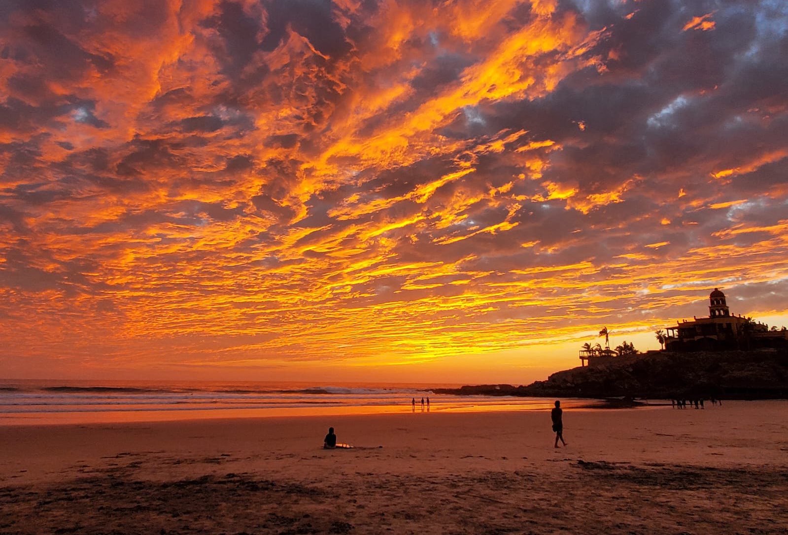 Surfers at Cerritos Beach as the sun sets over the Pacific