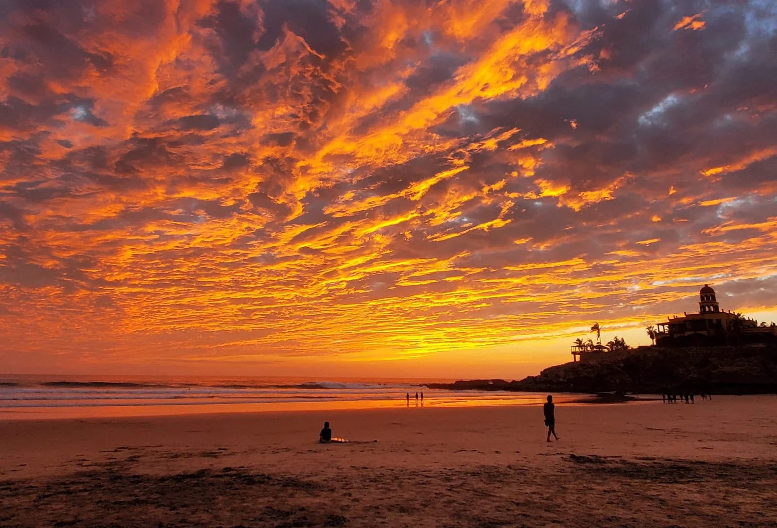 Surfers at Cerritos Beach as the sun sets over the Pacific